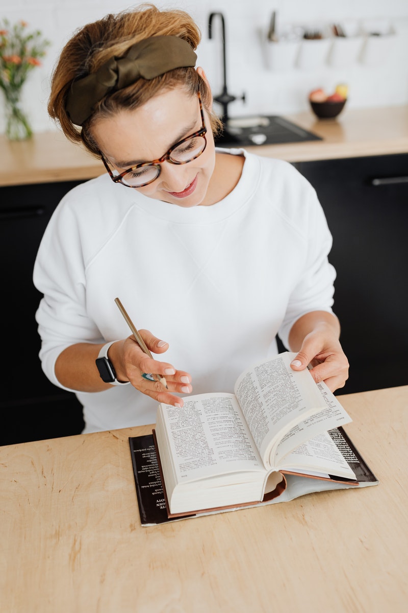 Woman in White Crew Neck Shirt Writing on White Paper